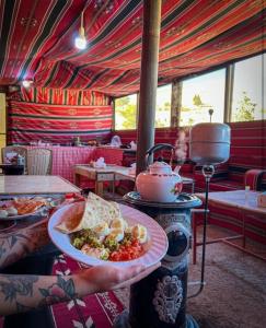 una persona sosteniendo un plato de comida en un restaurante en 7 Caves Hotel en Al Jāyah