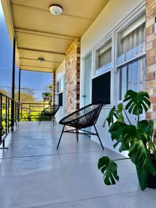 eine Veranda mit 2 Stühlen und einem TV auf einem Gebäude in der Unterkunft Ringtails Motel in Busselton