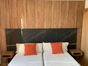 Una cama blanca con dos almohadas naranjas. en Pensión Da Estrela, en Santiago de Compostela