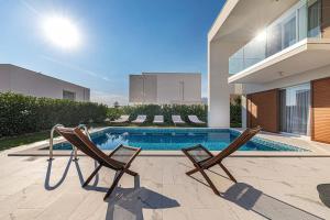 una piscina con due sedie accanto a una casa di Luxury Villa Tina Moseni with private heated pool a Kaštela (Castelli)