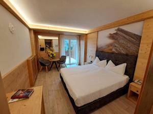 une chambre d'hôtel avec un lit et une table dans l'établissement Lake&Nature Hotel Gloria, à Molveno