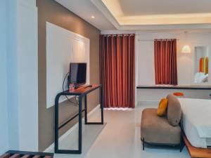 卡拉旺的住宿－Sans Hotel Grand Sabaraya Cikampek，配有床、电视和椅子的房间