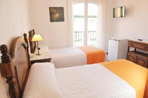 a hotel room with two beds and a window at Hostal Puerto Lepe in Lepe