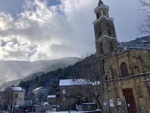 an old stone building with a clock tower with mountains in the background at U Vechju Fragnu in Vezzani