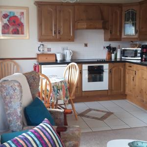 a kitchen with wooden cabinets and a table and chairs at Armada Lodge Seashore Holiday Apartment in Grange