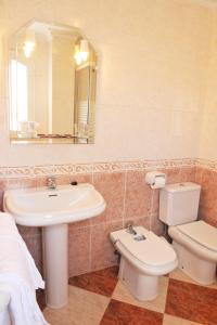 a bathroom with a sink and a toilet and a mirror at Hostal Puerto Lepe in Lepe