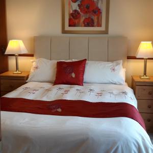 a bedroom with a bed with red pillows and two lamps at Armada Lodge Seashore Holiday Apartment in Grange