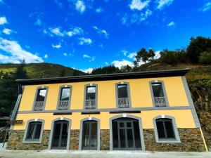 a yellow building with white windows on a hill at Hotel Cadario 1925 in Tebongo