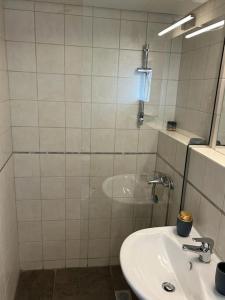 un bagno piastrellato bianco con lavandino e doccia di Acropolis View Apartment Athens Downtown ad Atene