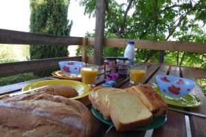 LES APPARTS DU VALINCO - VILLA 77 - CORSE 2A -ANCV في سيرا-دي-فيرو: طاولة خشبية مع الخبز والخبز المحمص وأكواب عصير البرتقال