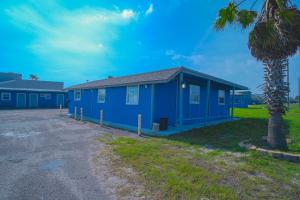 un edificio blu con una palma di fronte di Monterrey Motel Padre Island, Corpus Christi BY OYO a Corpus Christi