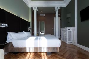 een slaapkamer met een groot wit bed met witte kussens bij Petit Palace Lealtad Plaza in Madrid