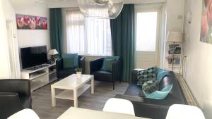 sala de estar con sofá, sillas y TV en Vakantiehuis Seahorse en Egmond aan Zee