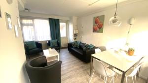 a living room with a black couch and a table at Vakantiehuis Seahorse in Egmond aan Zee