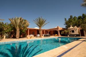 una piscina con palmeras y una casa en L’oasis de kima en Taroudant