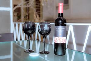 een fles wijn en twee wijnglazen op een tafel bij Plaka Apartment in Athene