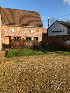 a brick house with a stone wall next to a driveway at Appartement lumineux et calme in Jodoigne