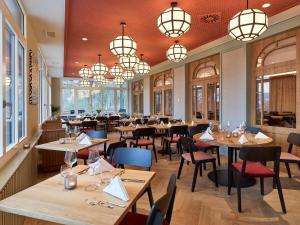 un restaurante con mesas, sillas y lámparas de araña en Boutique Hotel Waldhaus beider Basel, en Basilea