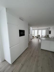 a white kitchen with white cabinets and a wooden floor at Strandferie på Sørlandet in Kristiansand