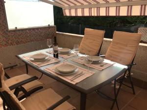 einen Tisch mit Tellern und Weingläsern auf einer Terrasse in der Unterkunft Apartamento con piscina a escasos metros de A Lanzada in Pontevedra