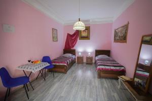 a room with two beds and a table and chairs at Leon Rooms in Tbilisi City