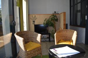 uma sala de estar com duas cadeiras, uma mesa e uma televisão em Gite Du Petit Coteau em Vouvray