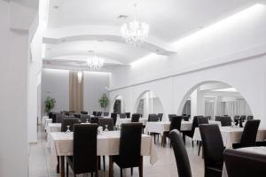 un comedor con mesas blancas y sillas negras en Hotel Apollo Central, en Sibiu