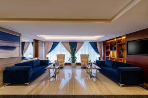 sala de estar con sofás azules y TV en Blue Diamond Hotel en Yeda
