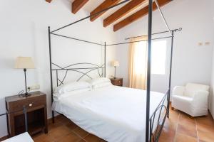 um quarto com uma cama de dossel e uma cadeira em Villas Finesse By MENORCARENTALS em Son Bou