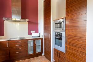 a kitchen with red walls and wooden cabinets at Villas Finesse By MENORCARENTALS in Son Bou
