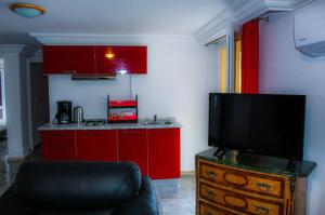 a kitchen with red cabinets and a flat screen tv at Résidence Les Camélias in Tabarka