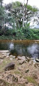 una corriente de agua con rocas y árboles en el fondo en Pousada Morretes Arraial, en Morretes