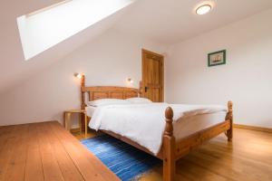 a bedroom with a wooden bed with white sheets at House Jelenko in Bovec