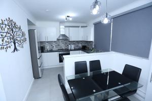a kitchen and dining room with a glass table and chairs at Abbeywood Station House London in London