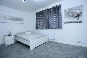 1 dormitorio con 1 cama y 2 cuadros en la pared en Abbeywood Station House London, en Londres