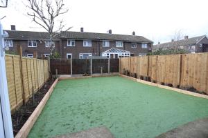 a backyard with a green lawn in front of a fence at Abbeywood Station House London in London