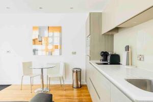 a white kitchen with a table and chairs in it at Canary wharf Luxury apartment in London