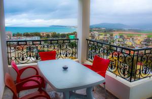 a balcony with a white table and red chairs at Résidence Les Camélias in Tabarka