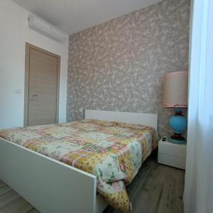 1 dormitorio con 1 cama con colcha de flores y lámpara en Piazza Mazzini 21, en Loano