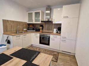 cocina con armarios blancos y mesa de madera en Heideherz en Soltau