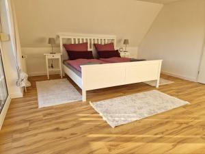 a bedroom with a bed with red pillows and two rugs at Heideherz in Soltau