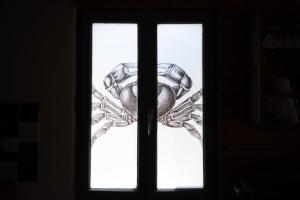 una puerta con una ventana con un objeto metálico en La Petite Maison De Papaye, en Le Palais