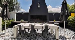 eine Terrasse mit einem Tisch, Stühlen und einem Kamin in der Unterkunft House of Pinardt in Robertson