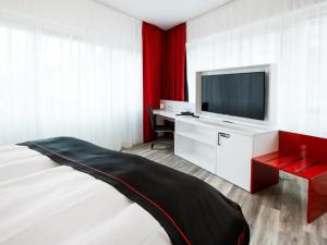 uma sala de estar com uma televisão e uma cama em DORMERO Hotel Hannover-Langenhagen Airport em Hanôver