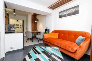 a living room with an orange couch and a kitchen at Ioana Residence Bucovina in Câmpulung Moldovenesc