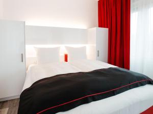 um quarto com uma cama com uma cortina vermelha em DORMERO Hotel Hannover-Langenhagen Airport em Hanôver