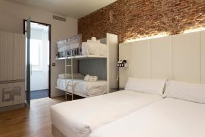1 dormitorio con 2 camas y pared de ladrillo en Petit Palace Lealtad Plaza, en Madrid