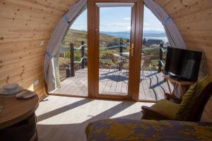 a living room with a large window and a television at Arranmore Glamping in Aphort