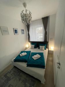 - une chambre dotée d'un lit avec des draps bleus et un lustre dans l'établissement Phoenix Luxury Apartment, à Oradea