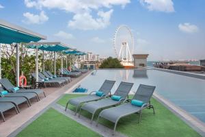 a pool with chairs and a ferris wheel in the background at JA Ocean View Hotel in Dubai
